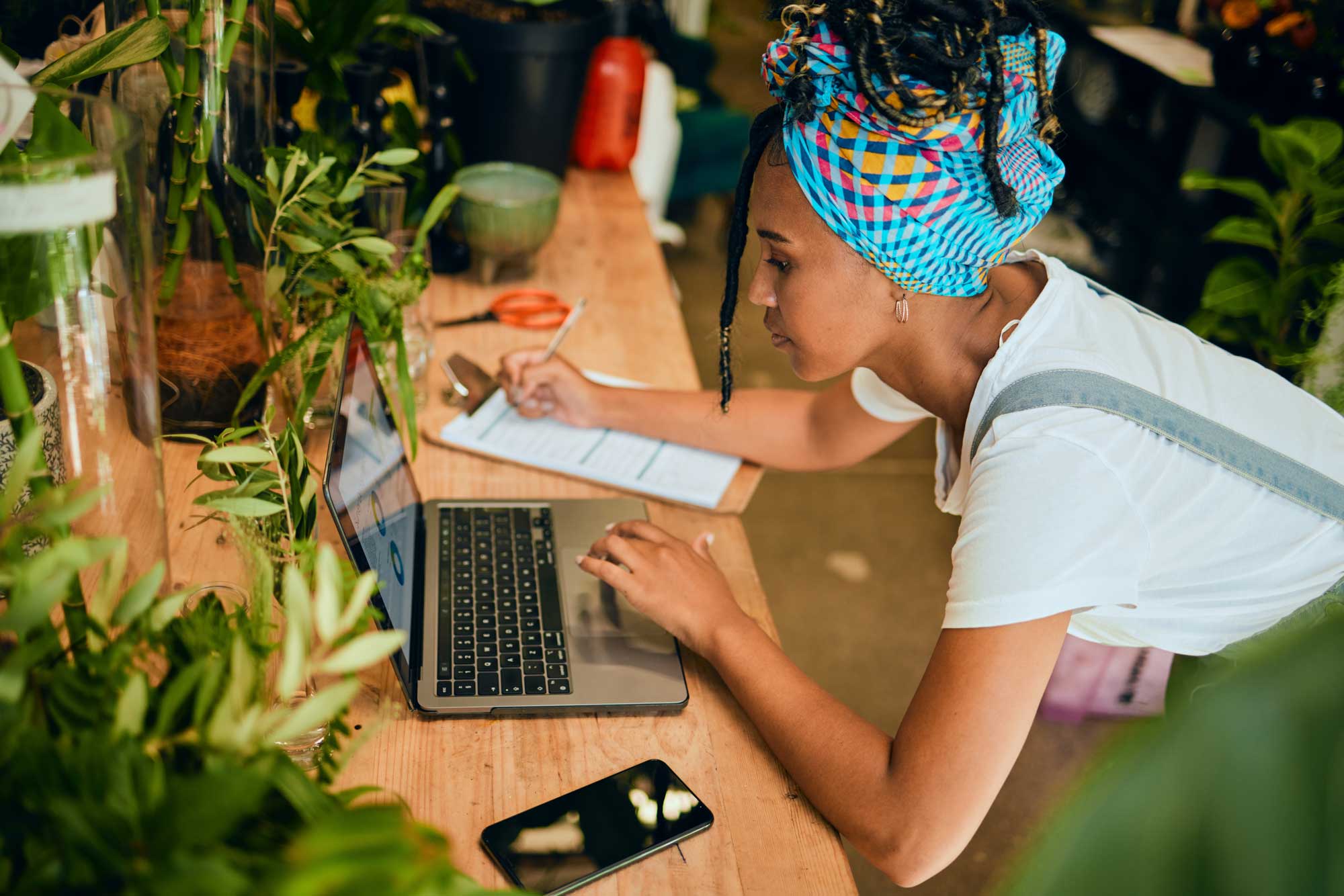 Laptop, small business or black woman writing a checklist on plants or flowers for commerce or stock inventory