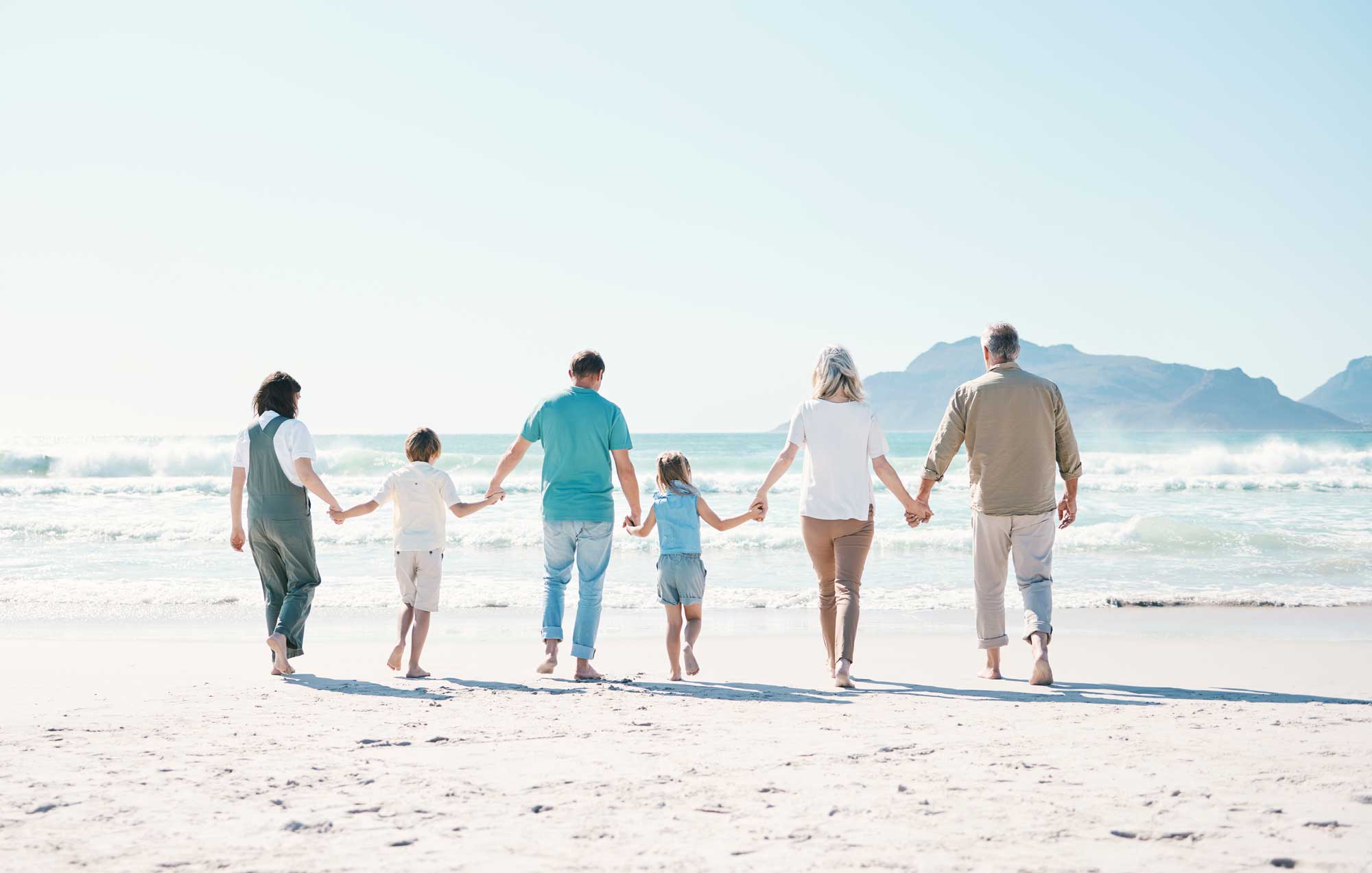 three generations of family walking on beach